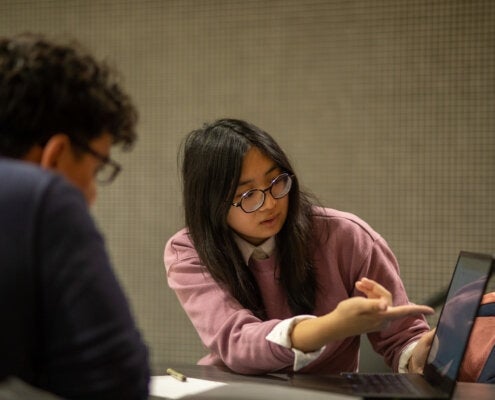 Engineering students pointing at a laptop, having a discussion